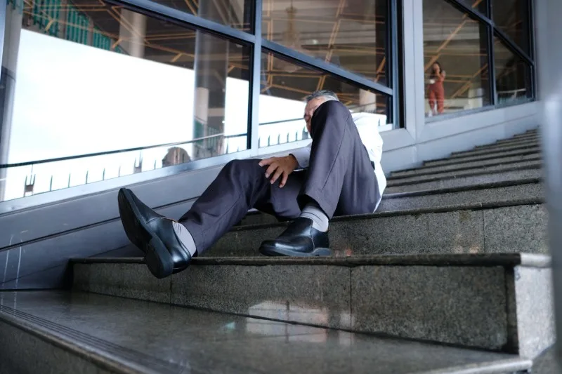 Person in business suit fallen on outdoor steps
