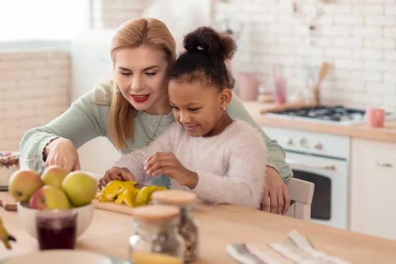 Adult and child preparing fruit at kitchen table