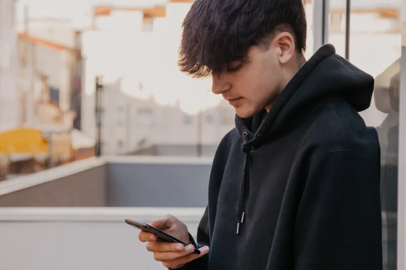 Young person standing outdoors using smartphone