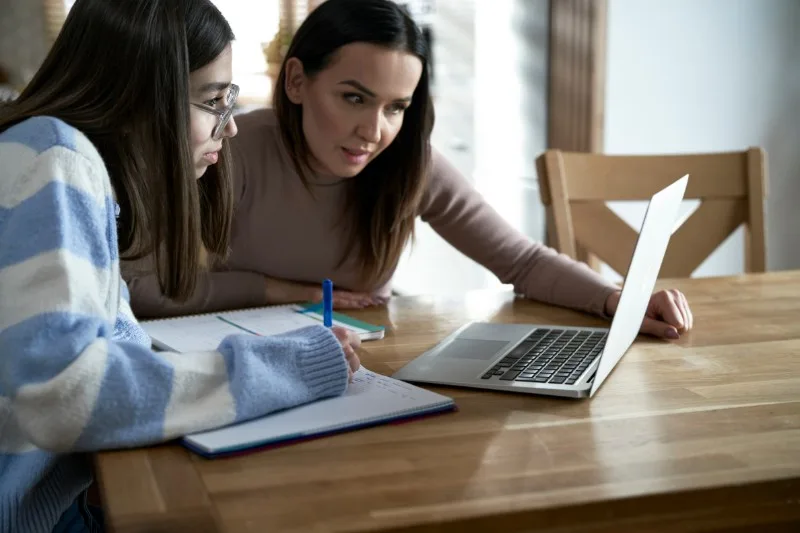 Adult and teenager working at laptop together