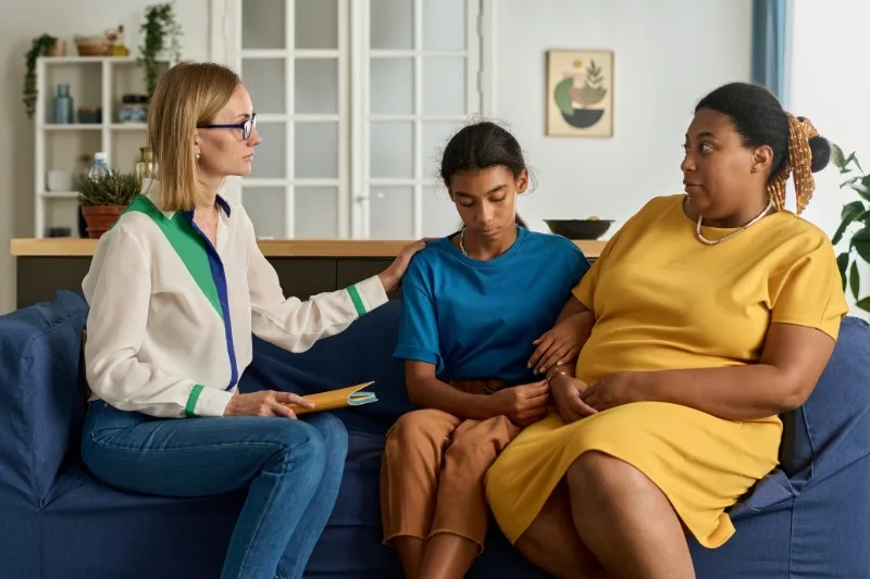 Three people sitting on a couch during conversation