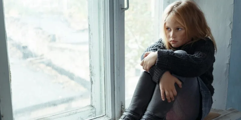 Child sitting alone by a window