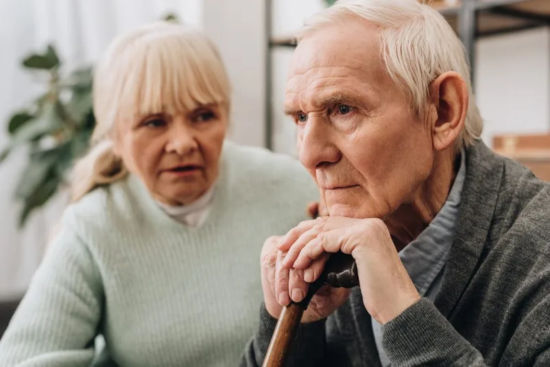 Elderly man looking troubled with cane
