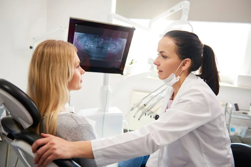Female dentist speaking to female patient in dental chair