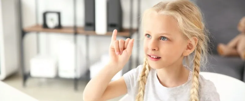Young girl signing with raised index finger