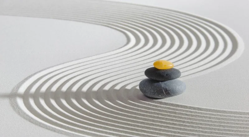 stacked stones on raked sand with curved lines