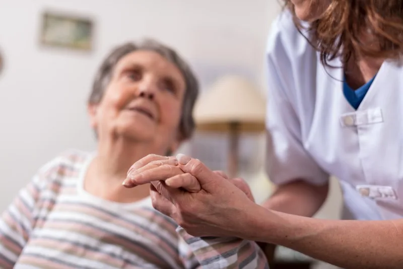 Caregiver holding an elderly woman's hands