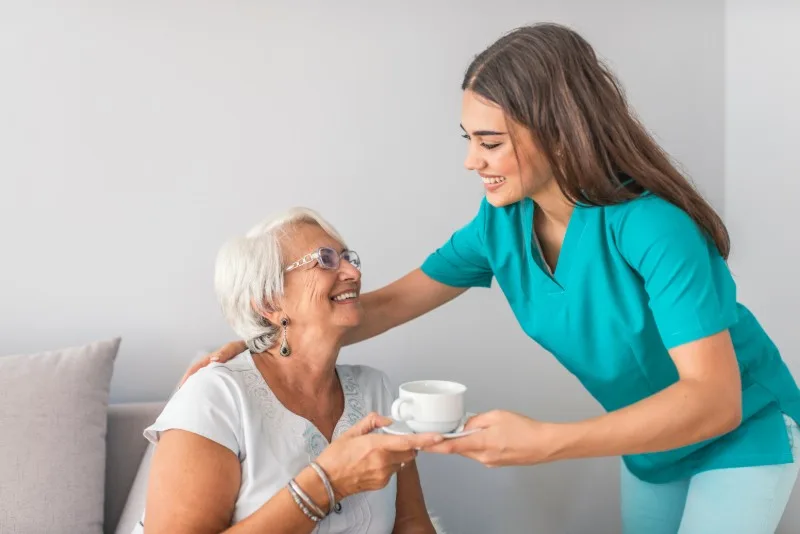 Caregiver handing a cup to an older woman