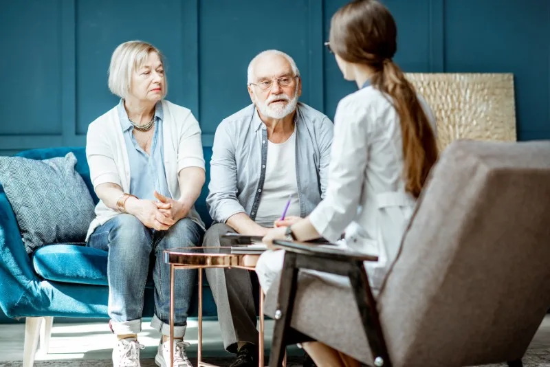 Elderly couple talking with a seated professional