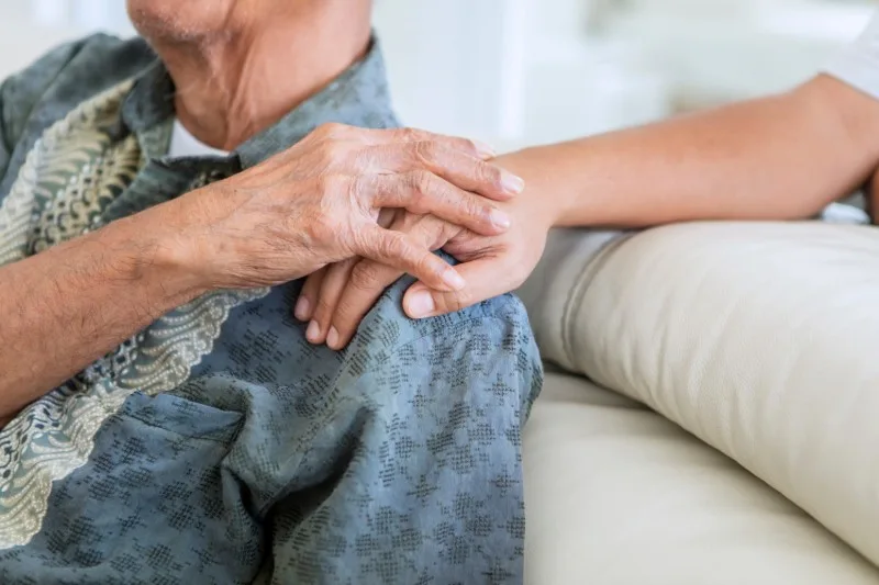 Older person holding caregiver's hand