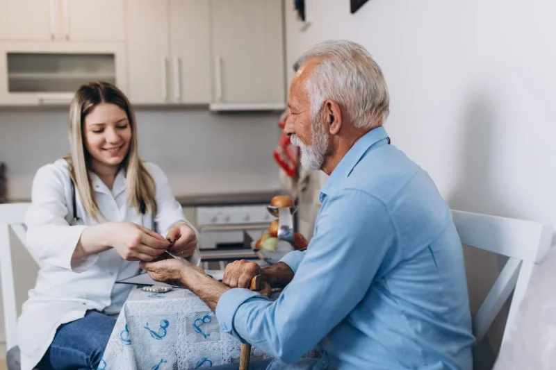 Care worker checking an older man's hand