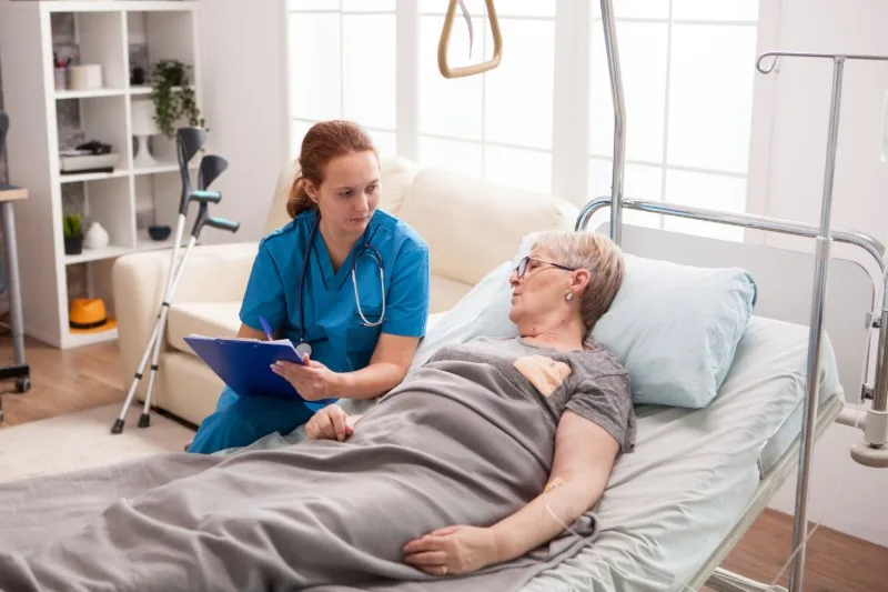 Caregiver speaking with older woman in bed
