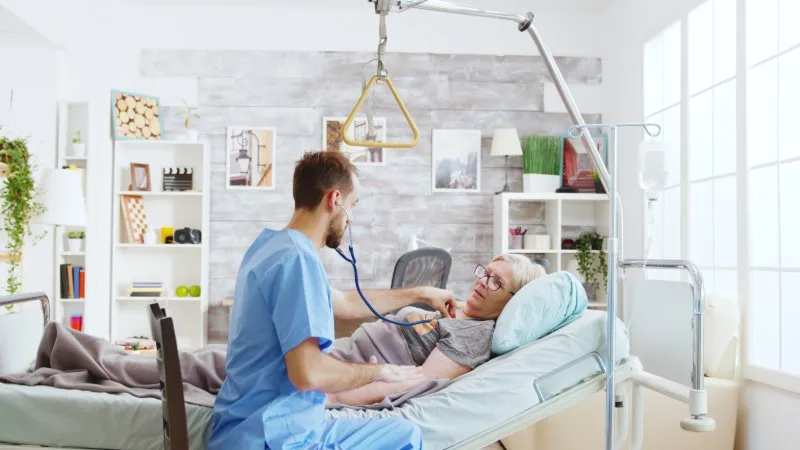Healthcare worker checking elderly patient in bed