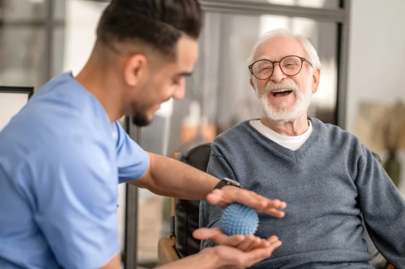 Care worker offering a stress ball to an older man