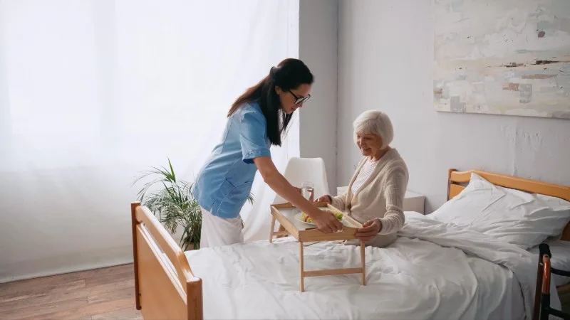 Caregiver assisting elderly person in bed