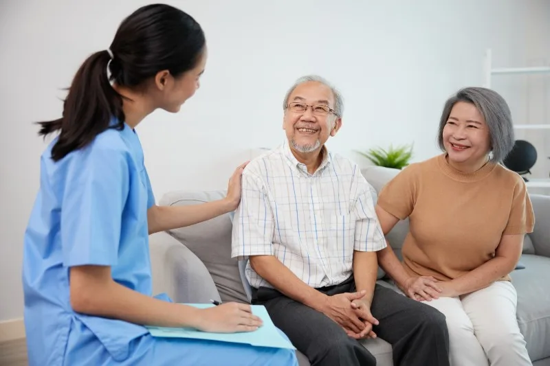 Care worker talking with an older couple on a sofa