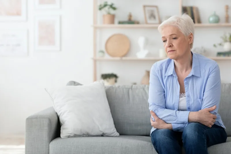 Older woman sitting alone on couch