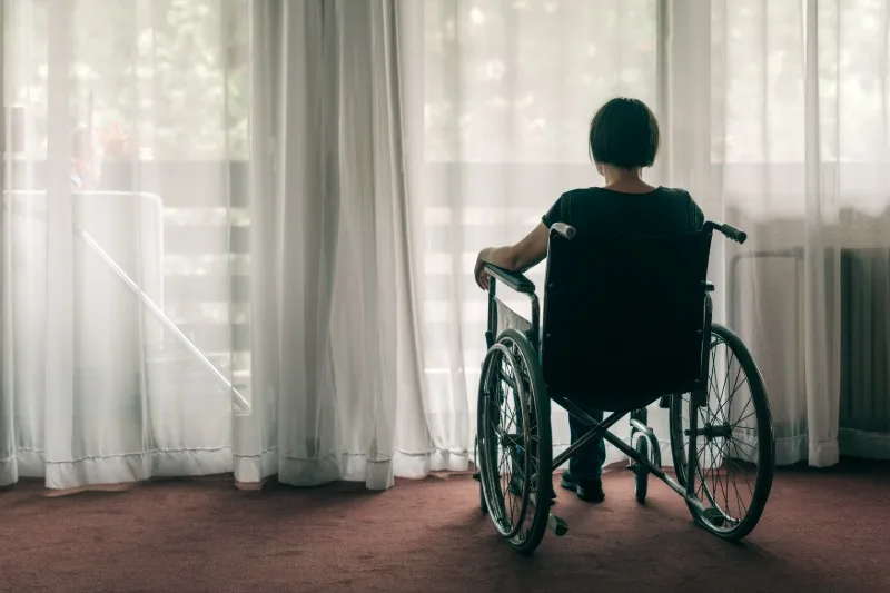 Person sitting in wheelchair facing window