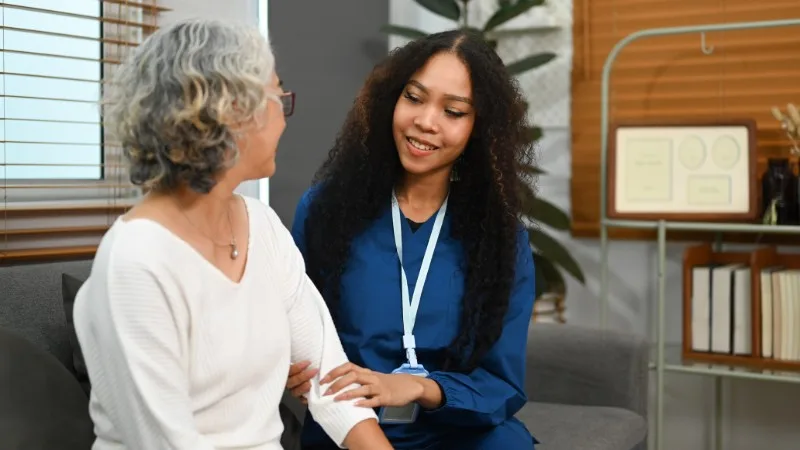 Care worker speaking with older woman on sofa