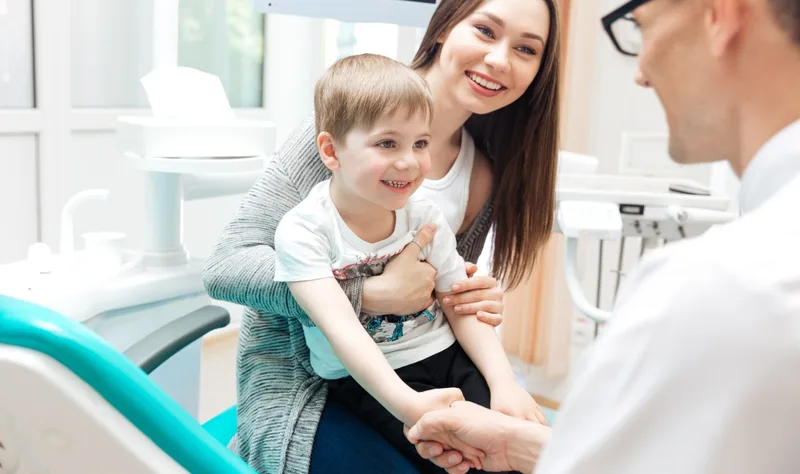 Mother holding young boy in dental chair