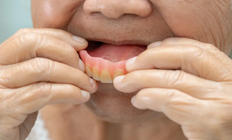 Elderly person removing upper denture