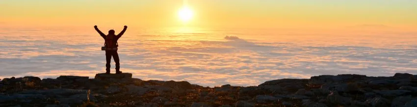 Person celebrating at the top of a mountain