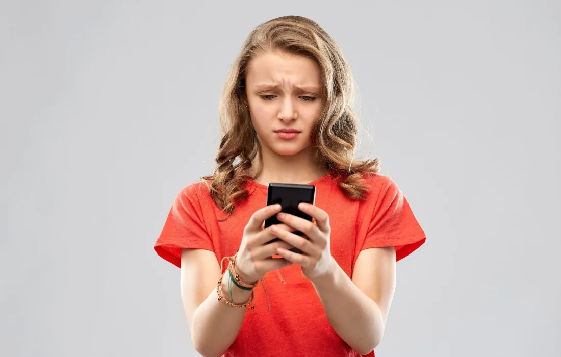 Young woman looking at smartphone with concerned expression