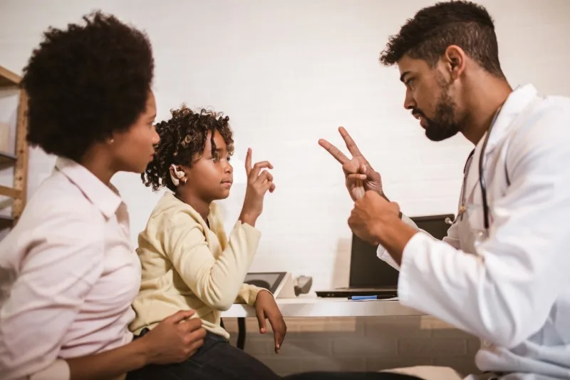 Child using sign language with clinician