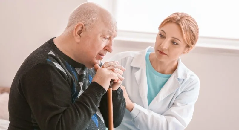 Caregiver speaking with elderly man holding cane