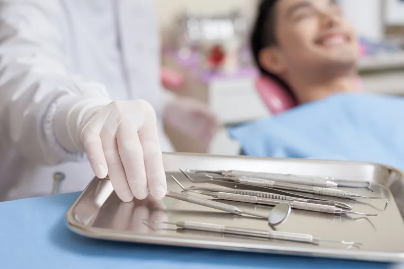 Dental instruments on metal tray near patient