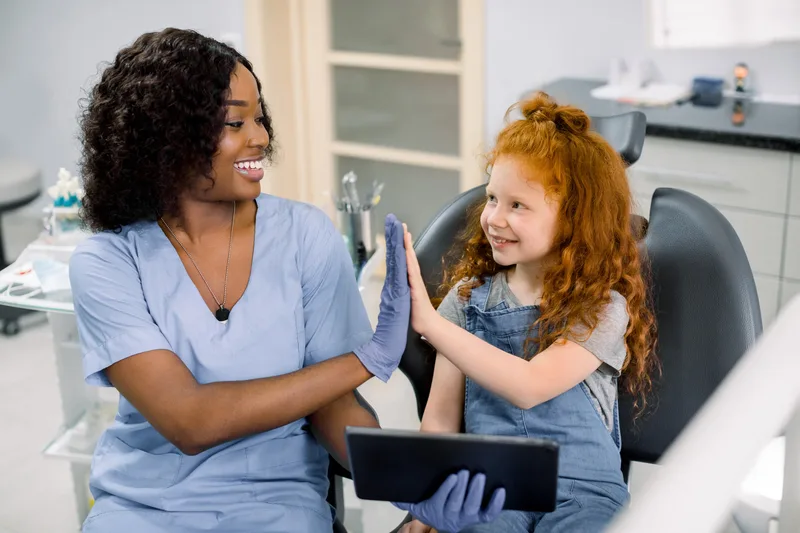 Smiling dental nurse and child high-five