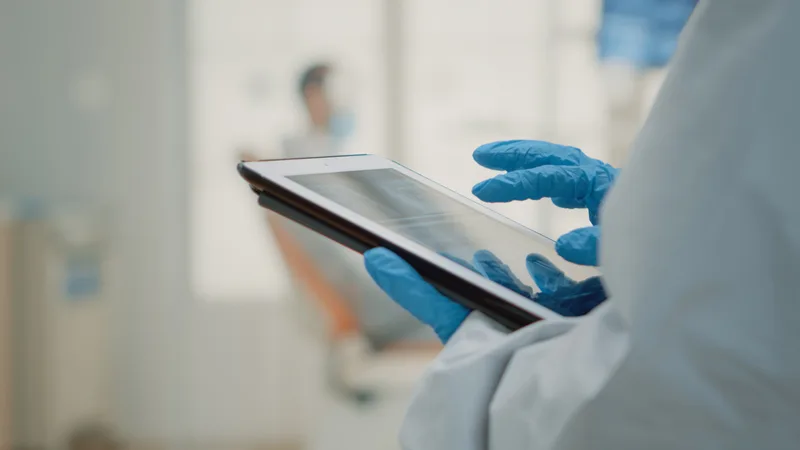 Gloved hands holding a tablet in a clinic