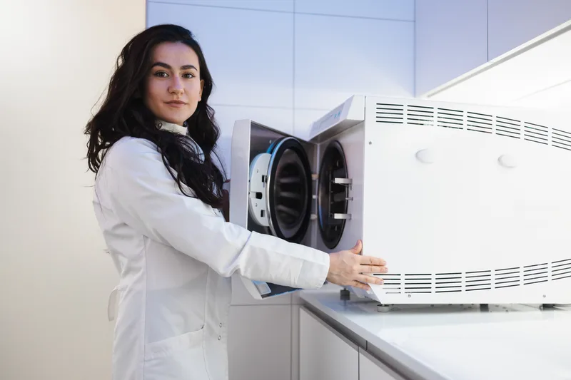 Female dental nurse loading autoclave sterilizer