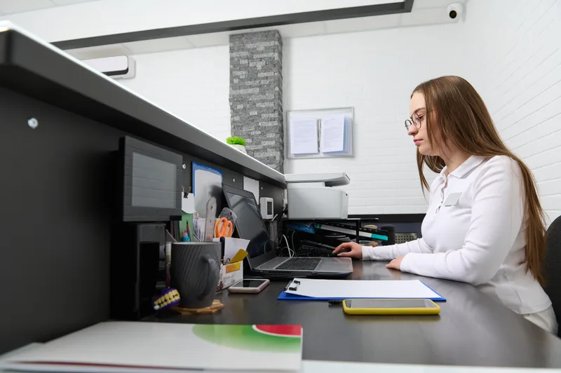 Young female dental receptionist at desk