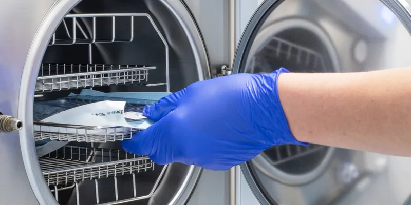 Gloved hand loading autoclave tray