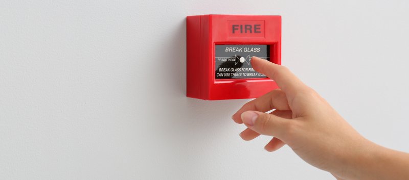 Hand about to press fire alarm break glass