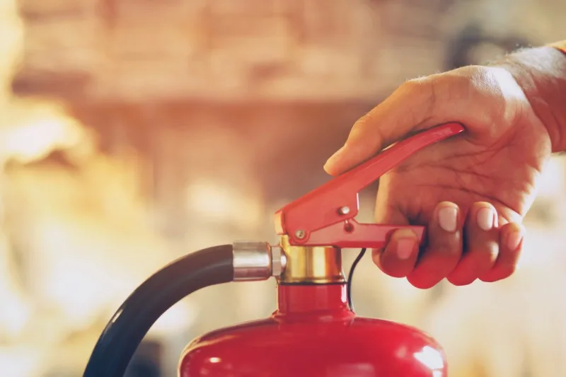Hand gripping a red fire extinguisher handle