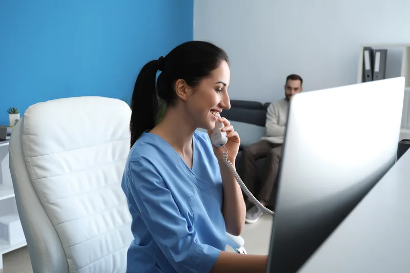 Female receptionist talking by phone in clinic