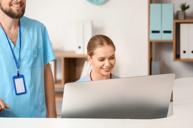 Male and female receptionists working at a clinic desk