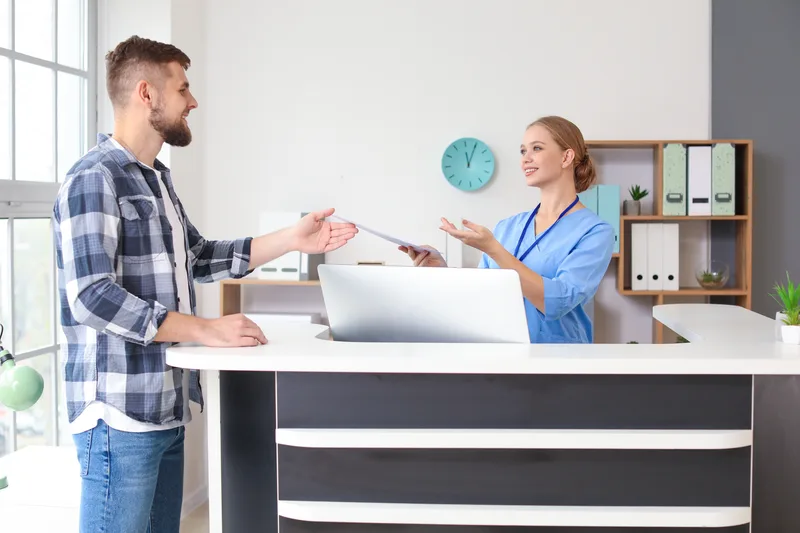 Receptionist working with a patient at a clinic desk