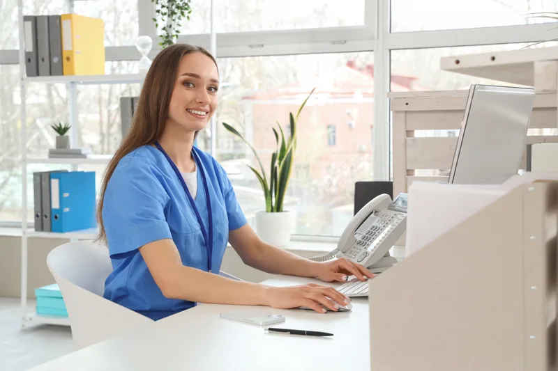 Female receptionist working with computer at clinic desk