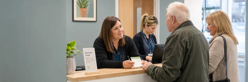 GP reception desk staff speaking with older patients
