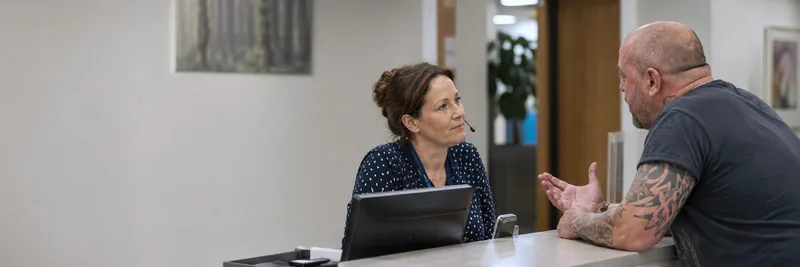 Female GP receptionist speaking with a male patient