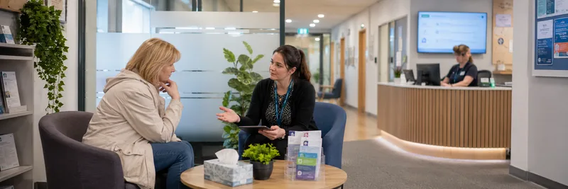 Two women talking in GP practice reception area