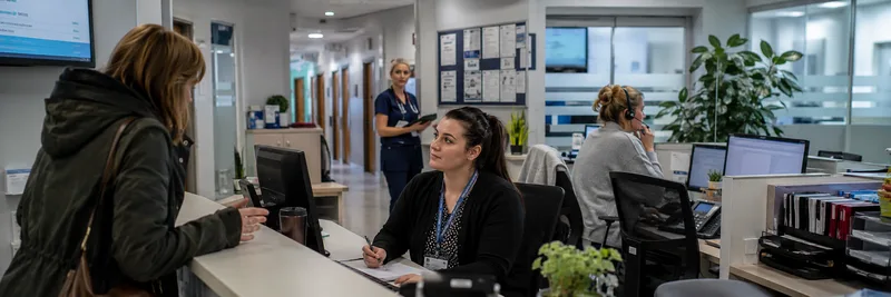 GP reception desk with staff assisting patient