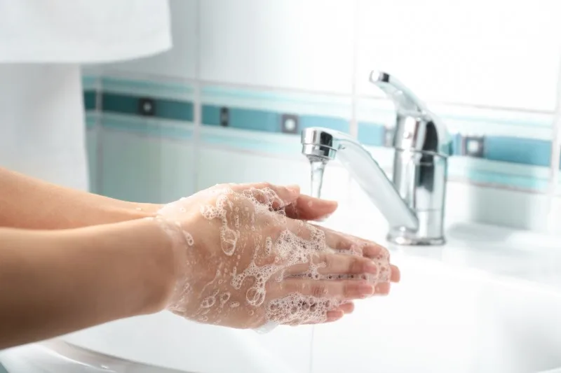 Hands being washed under faucet with soap