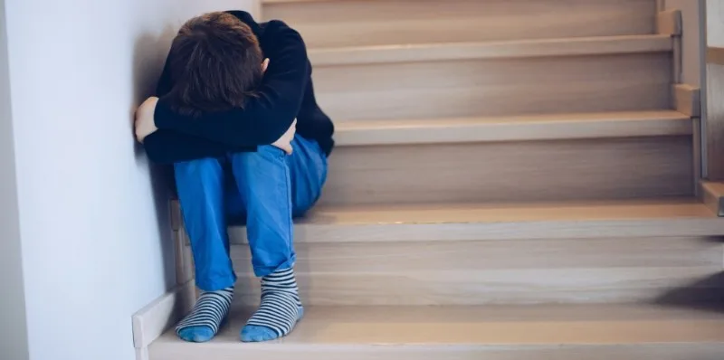 Child sitting alone on wooden stairs