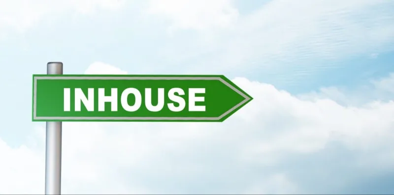 Green directional sign reading INHOUSE against sky
