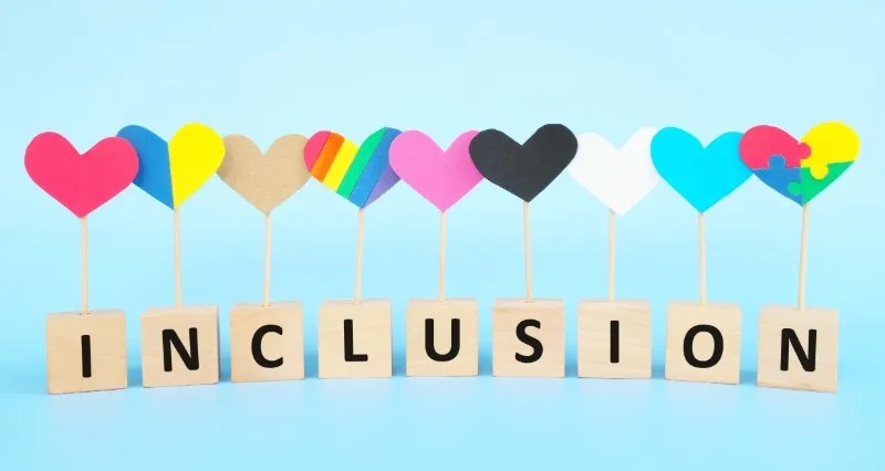 Wooden letter blocks spelling INCLUSION with heart icons