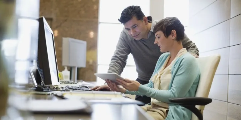 Two colleagues reviewing tablet at desk